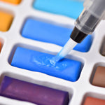 An aqua brush from the artist series watercolour paint set that has 24 colours, being used on a colour of paint - Stationery Island