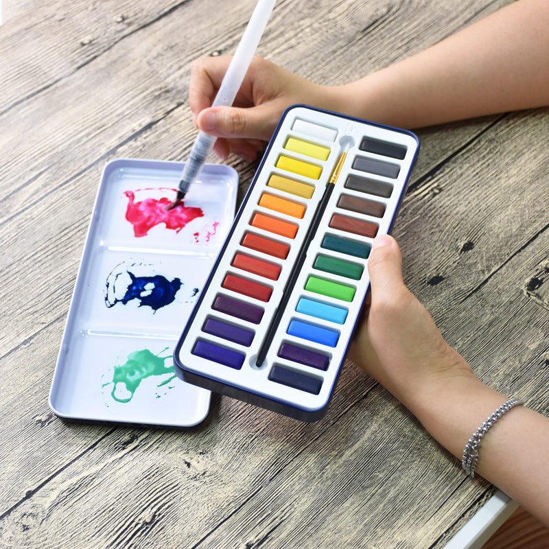 A person using the aqua brush to test paint colours on the lid of the artist series watercolour paint set that has 24 colours - Stationery Island