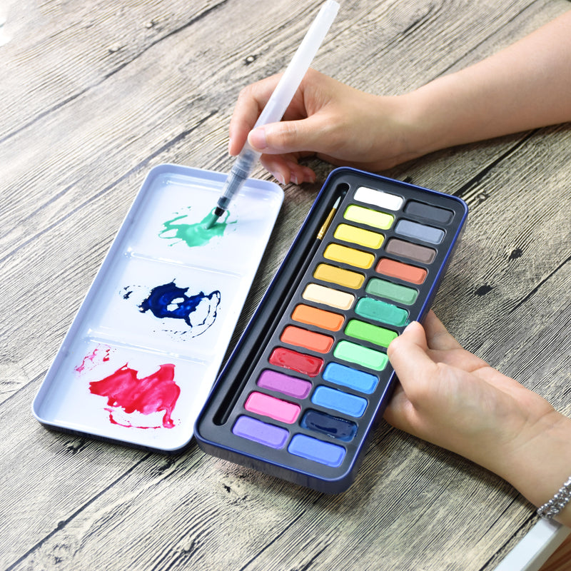 A person using the aqua brush to mix colours on the lid of the creative collection watercolour paint set that has 24 colours - Stationery Island