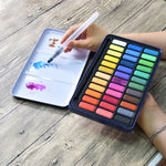 A person using the aqua brush to mix colours on the lid of the creative collection watercolour paint set that has 36 colours - Stationery Island