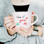 Acrylic paint pens used to write have a good day on mug with woman holding it - Stationery Island
