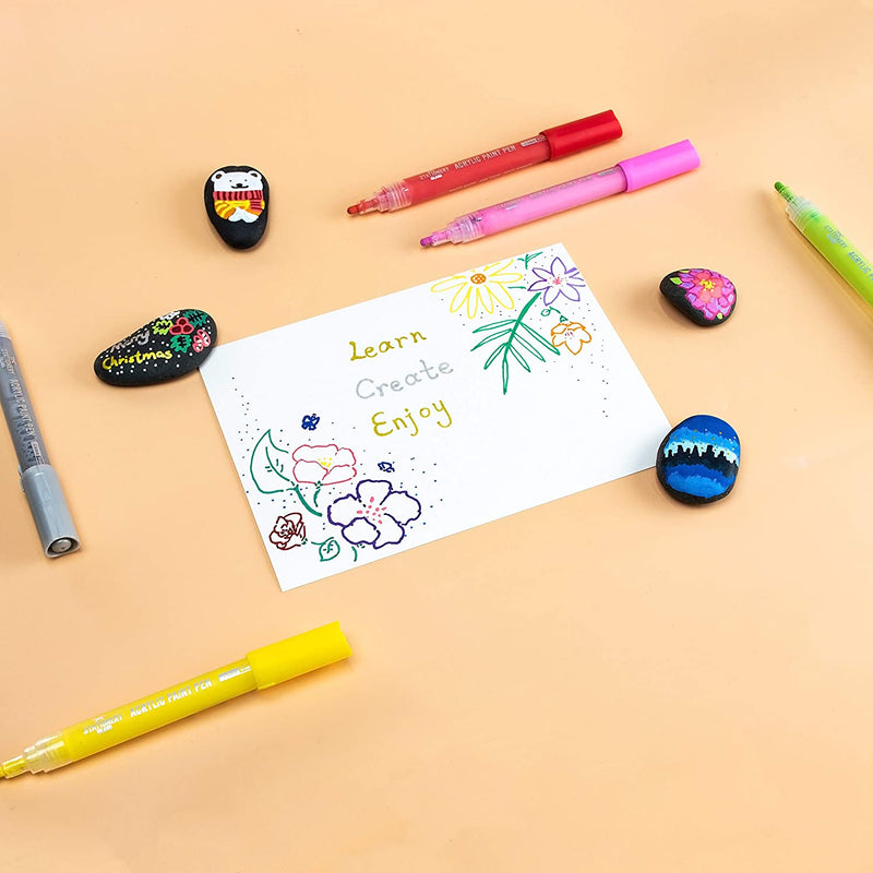 Acrylic paint pens put on the table with the flower drawing and rock drawings - Stationery Island