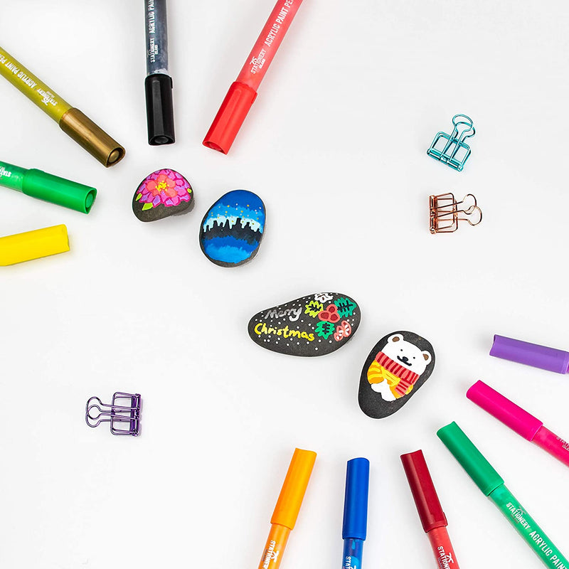 Acrylic paint pens facing each other with images drawn on rocks in the middle - Stationery Island