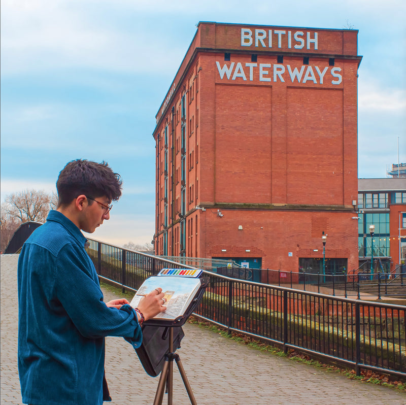 A man painting a scenic picture outside on the A4 artist grade watercolour paper pad with 300gsm paper and 50 pages - Stationery Island
