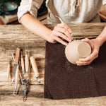 A woman sculpting a clay pot - Stationery Island